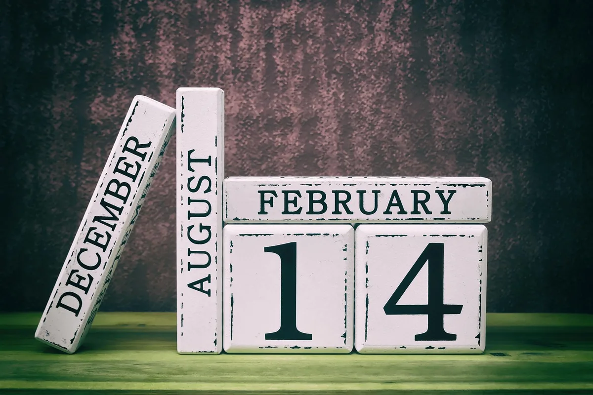 close-up of a calendar with dates circled in red and a pen lying across the page, desk lamp softly lit