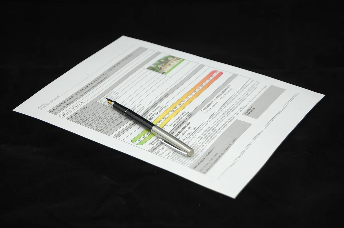 A well-lit desk with hands arranging printed training briefs, a French-language leaflet titled 'apprentissage' visible but unreadable, a pen and a small stack of neutral business cards