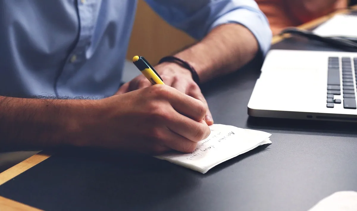 bright desk with open notebook, calculator and hands sketching a framework