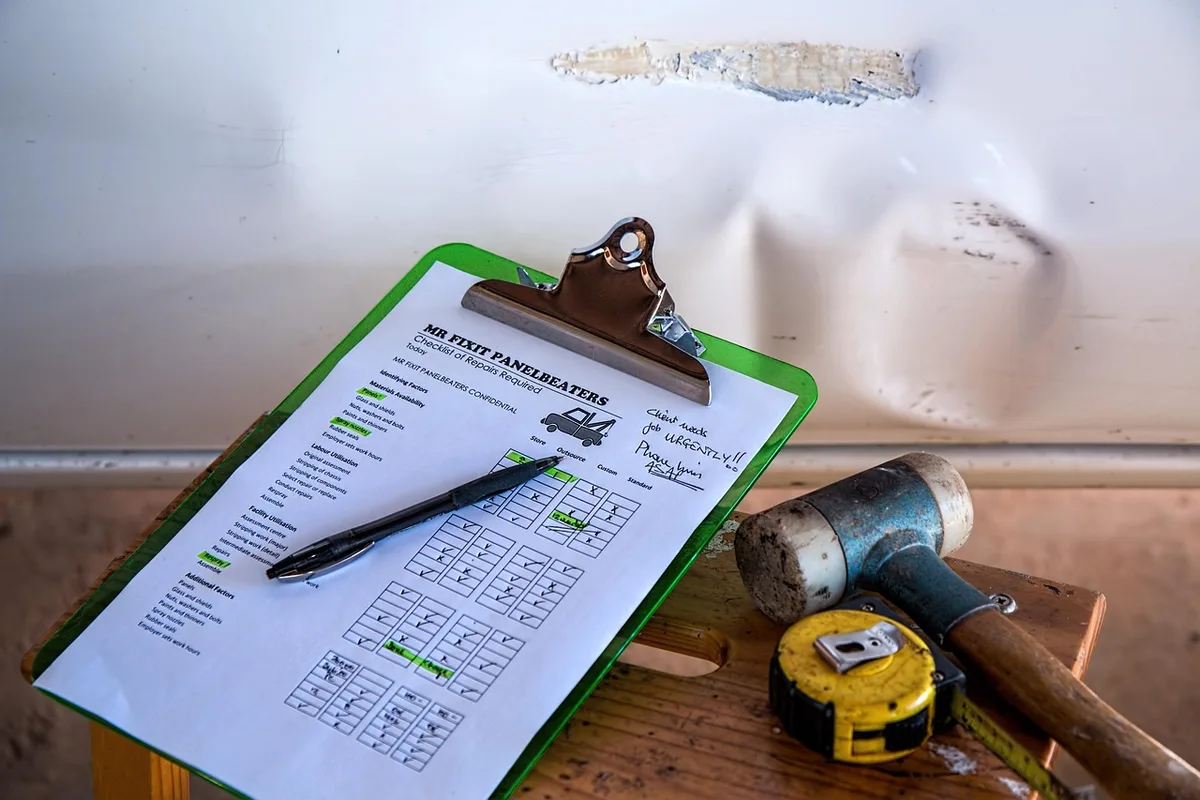 Toolkit on a desk with inspection checklist, hard hat off to the side, unbranded measuring tools and maintenance logbook visible