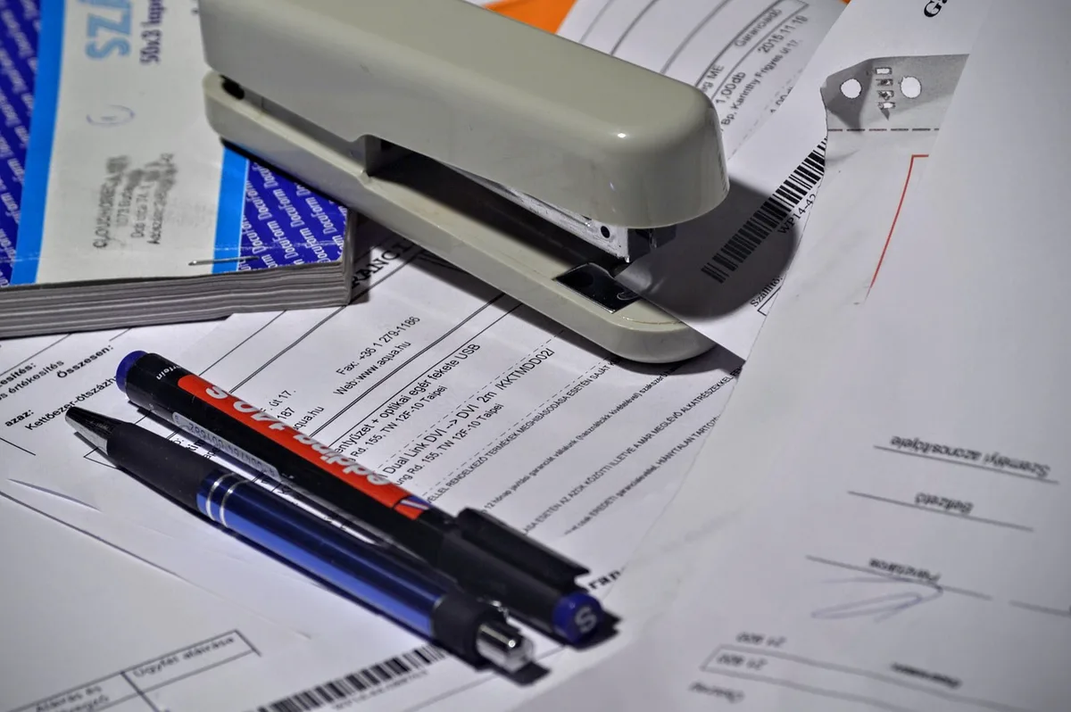 Close-up of hands holding financial documents and a calculator on a desk, with a blurred investment chart in the background