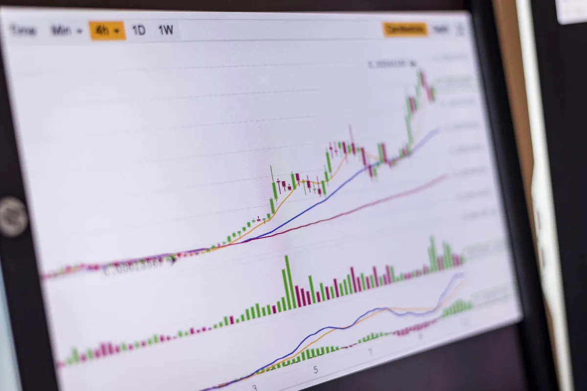 A neat desk with a laptop showing a stock index chart, a printed payoff diagram, and a pen resting nearby