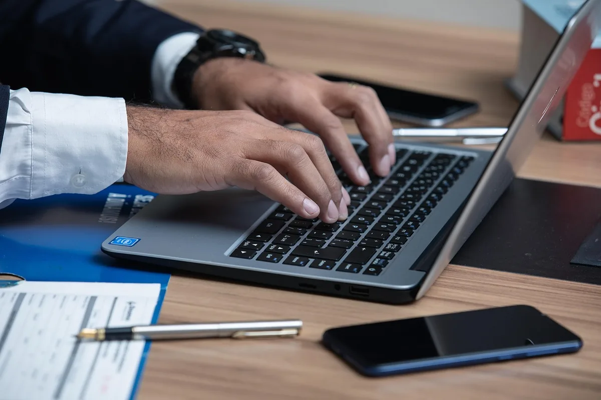Close-up of hands signing an employment notice on a desk with a generic folder and a stapled medical form nearby