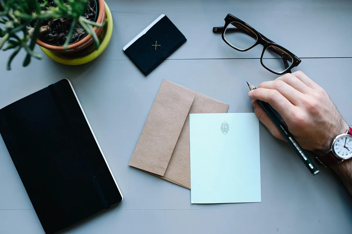 A tidy office desk with a closed folder labelled ‘medical’ (no logos), a pen and a pair of glasses, sunlight on the table