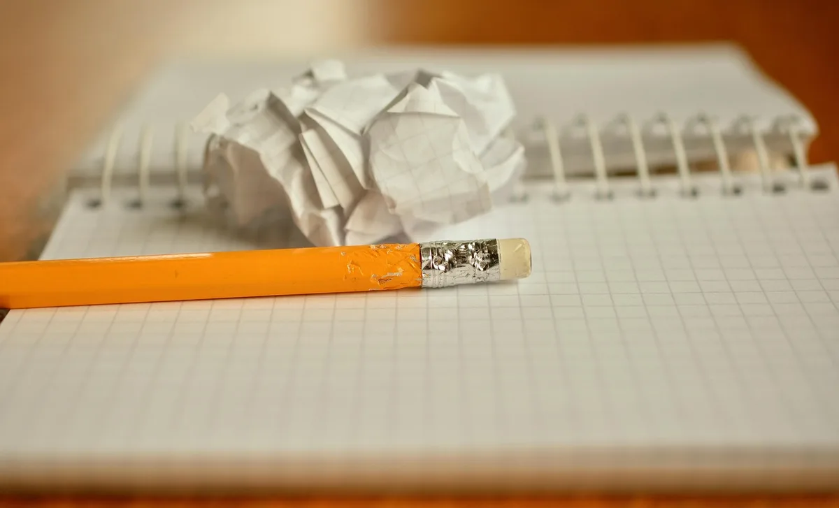 A tidy desk with printed PDF lists titled generically "admissibles", a pen and an open laptop showing a government web page
